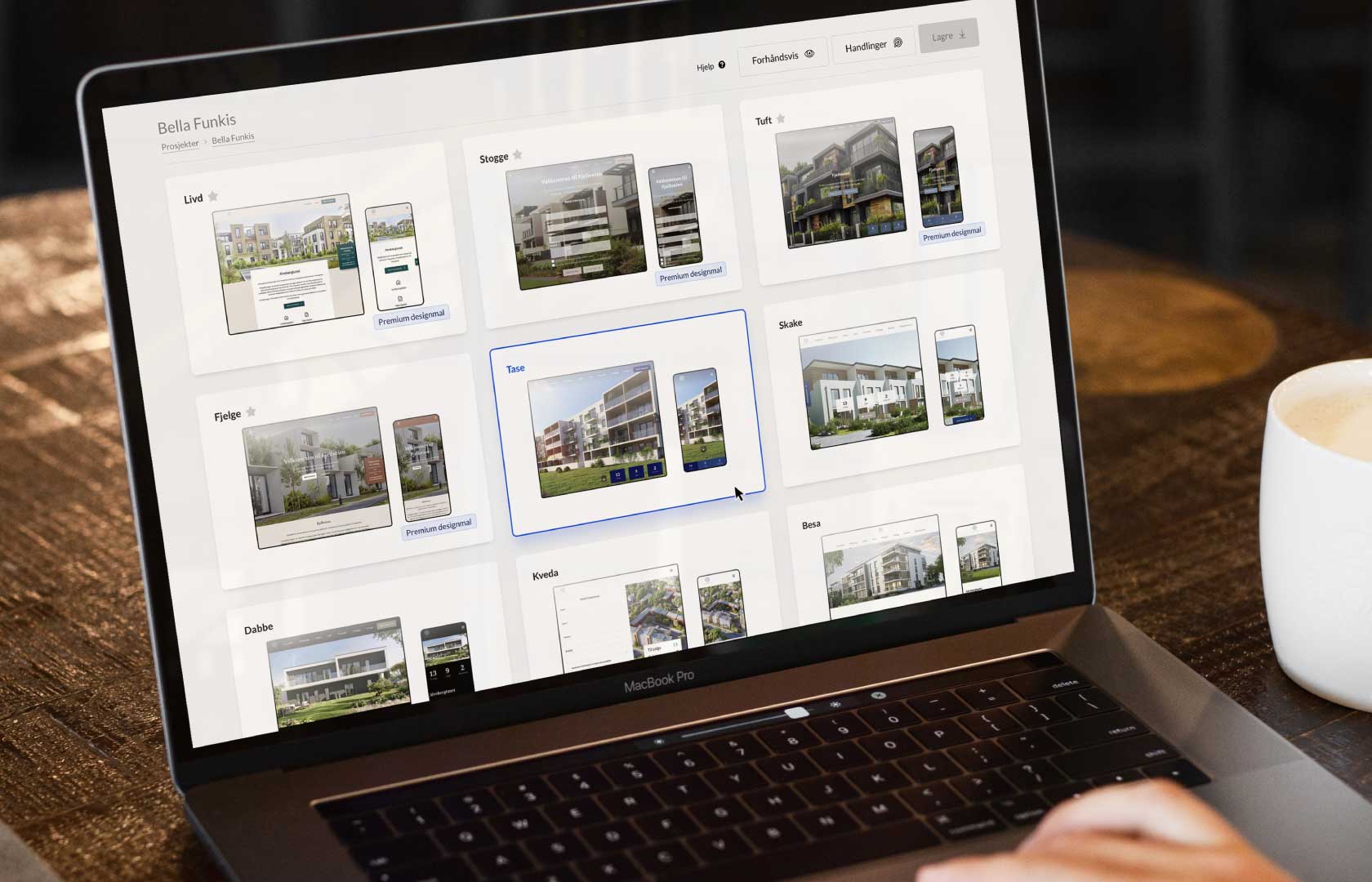En person arbejder på en laptop, der viser Kvass CMS-grænsefladen. Skærmen viser forskellige designskabeloner til ejendomsprojekter. Brugeren har valgt en færdig designmal. En kop kaffe står ved siden af computeren.